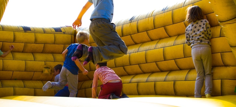 Children play and bounce on a bright yellow inflatable structure, captured mid-action with joyful expressions.