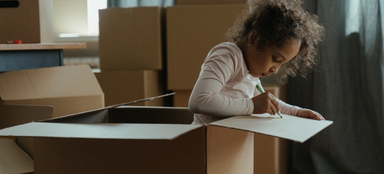Kid playing in a cardboard box, even small children need support before a move across the country