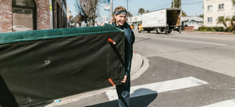 Mover carrying a green couch