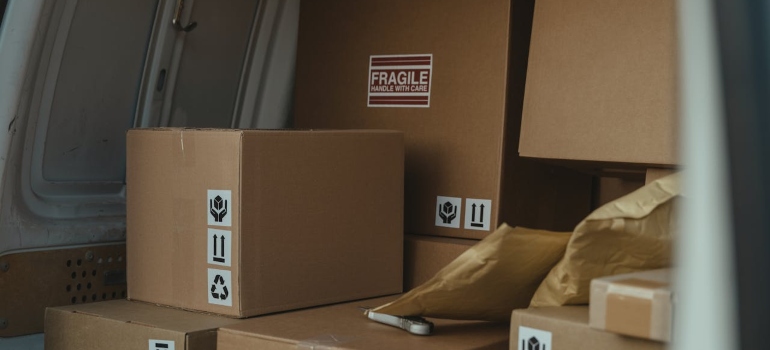 A van filled with packed cardboard boxes labeled "Fragile" and symbols indicating handling instructions.