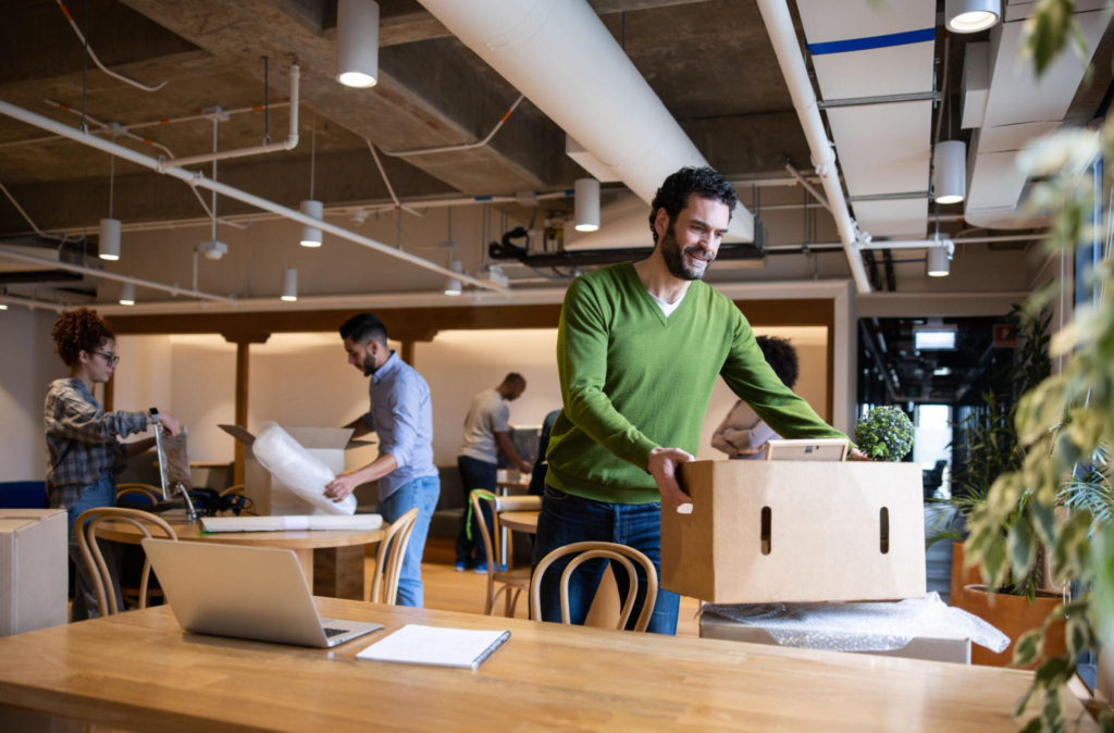 Professional residential movers carefully wrapping furniture with protective plastic inside a bright home during a local moving service